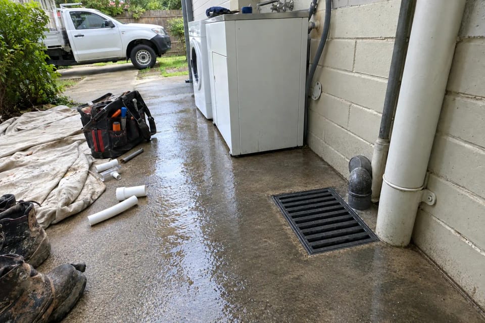 After: the same gully after the drain was cleared: grate clean, concrete hosed and drying.