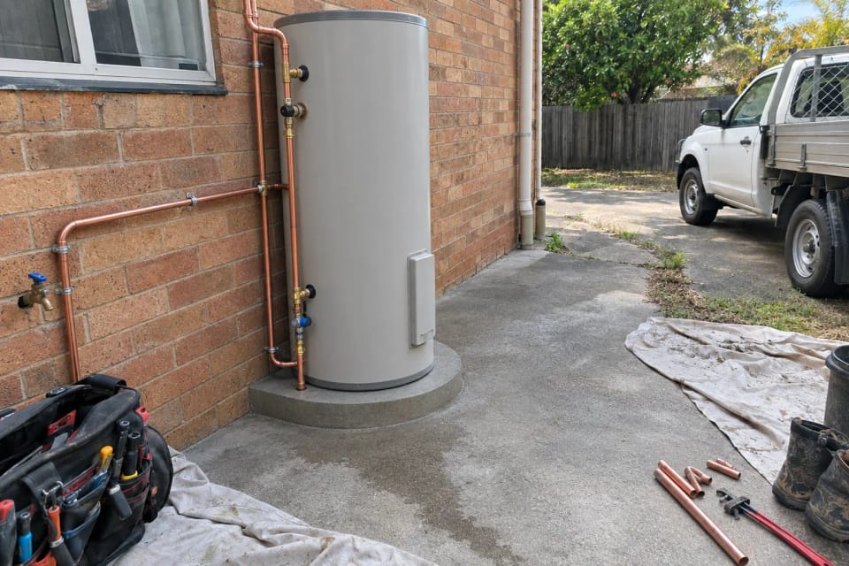After: the same spot after replacement: a new hot water system on a clean pad with new copper pipework.