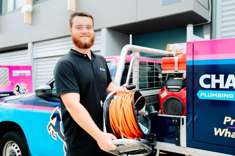 A Champion plumber lifting a hose reel off the truck.