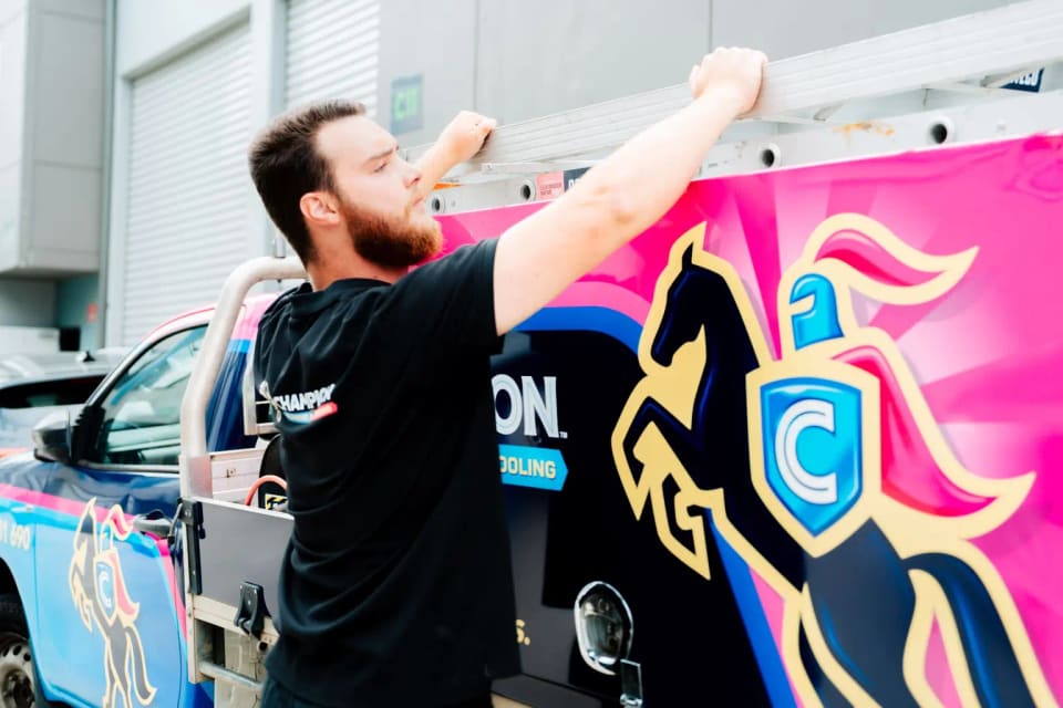 A Champion plumber taking the ladder off the truck.
