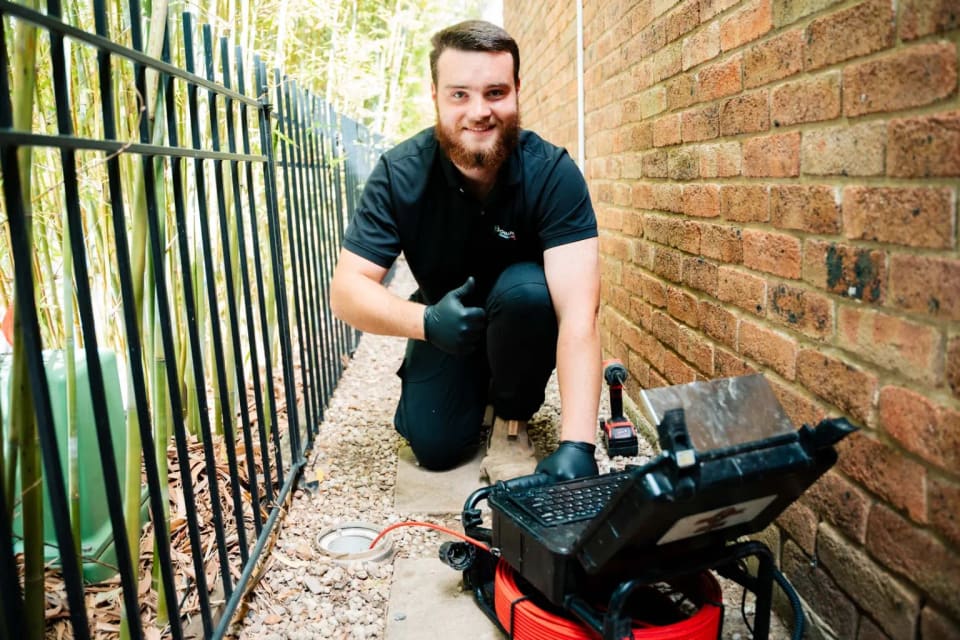 A Champion plumber with the drain camera, giving a thumbs up.